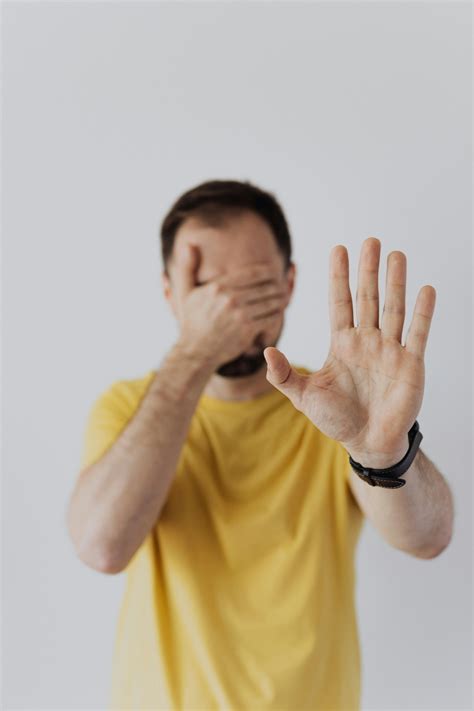 Man in Yellow Crew Neck T-shirt Wearing Black Watch Covering His Face · Free Stock Photo