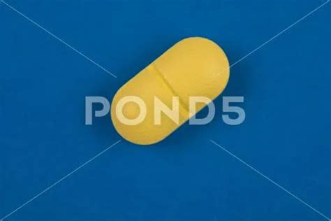 Oval shaped yellow pill in macro view isolated on blue background ~ Hi ...