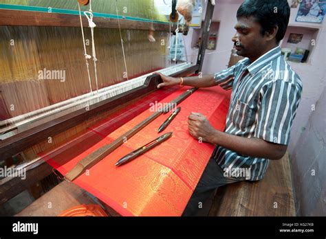 Silk weaver at his loom in his house, weaving sought after red and gold Kanchipuram silk sari ...