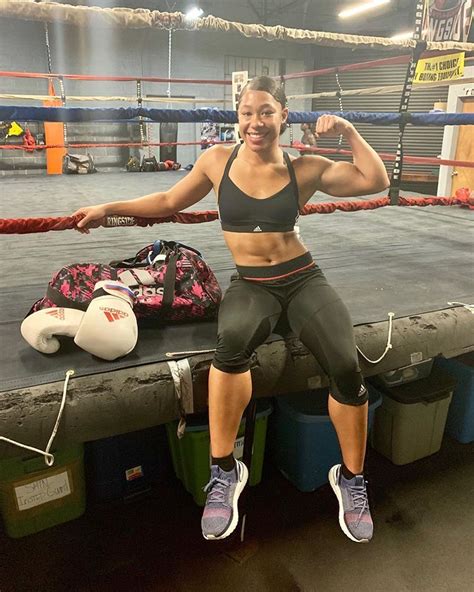 a woman sitting on the edge of a boxing ring posing for a photo in her ...