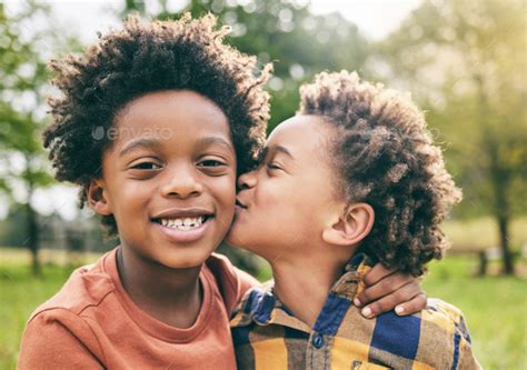 Portrait, kids and boy siblings kiss in a park for play, fun and siblings bonding in nature ...