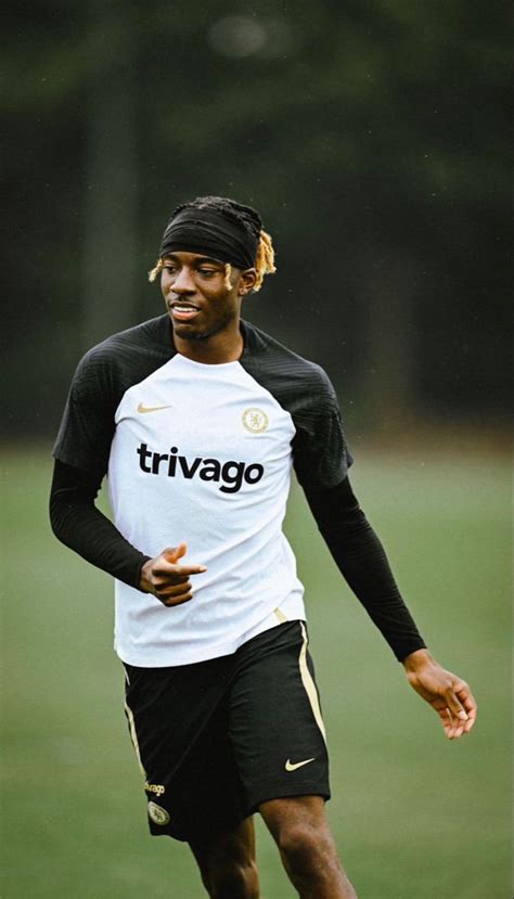 a young man running across a field wearing a black and white soccer ...