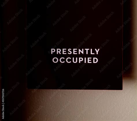 Black sign hanging on door that says Presently Occupied Stock Photo ...