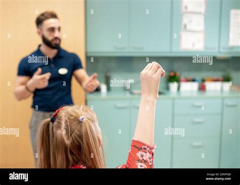 Girl raising hand in classroom Stock Photo - Alamy