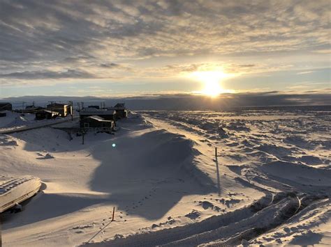 the sun is setting over some snow covered hills