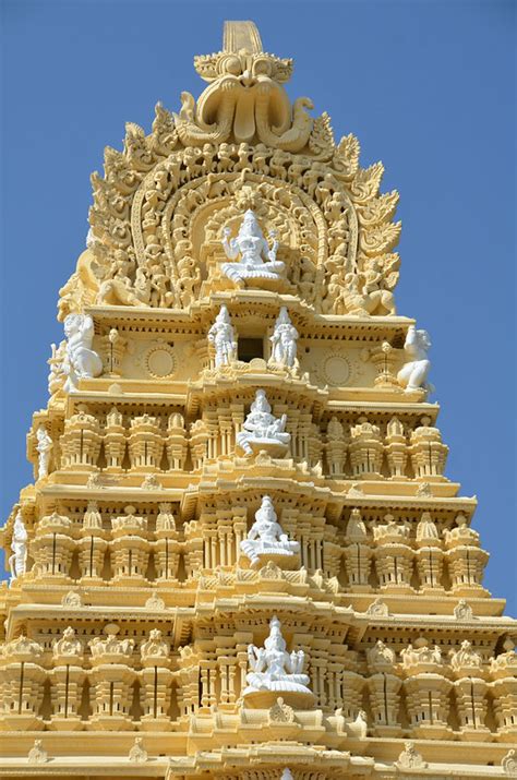 the top of a tall yellow building with statues on it