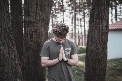 Premium Photo | Young man praying by trees on field