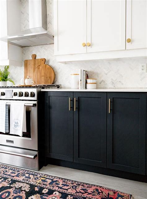 White kitchen uppers mixed with inky black base cabinets warmed with matte brass hardware and ...