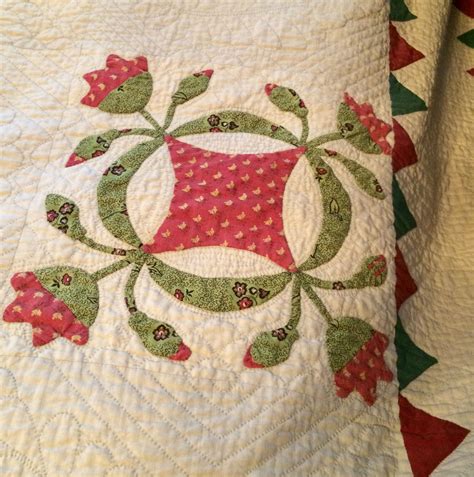 a close up of a quilt on a bed with red and green trimmings