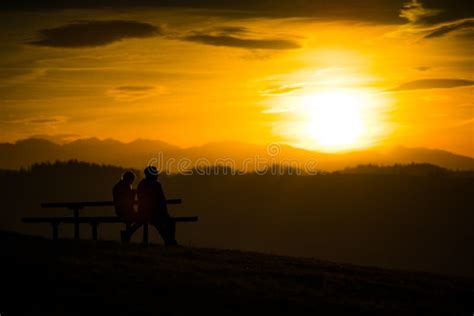 Couple Sitting on a Bench during a Sunset in the Mountains Stock Photo ...