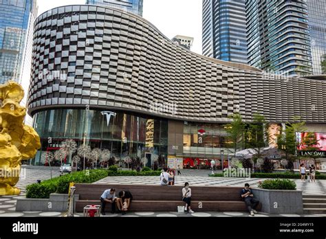 Exterior of modern shopping mall with people sitting in front in ...