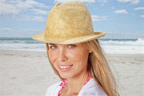 Portrait of smiling woman on beach in straw hat, Cape Town, South Africa - Stock Photo - Dissolve