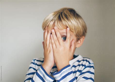 "Scared Child Peeking Between His Fingers" by Stocksy Contributor "Kelly Knox" - Stocksy