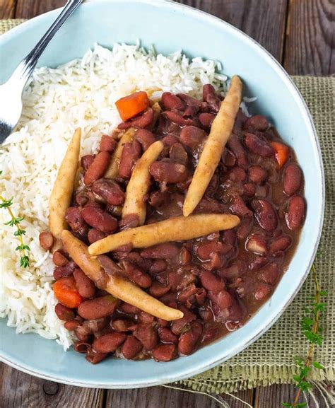 Close up Jamaican stew peas with spinners, carrots, on steamed rice in a blue bowl, stainless ...