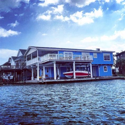 a boat is parked on the water in front of a blue house with white balconies