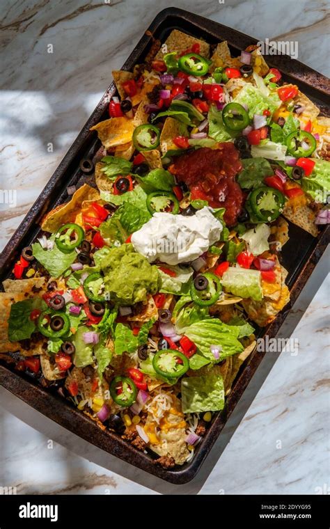 Loaded toppings beef nachos with guacamole sour cream and tomato salsa Stock Photo - Alamy