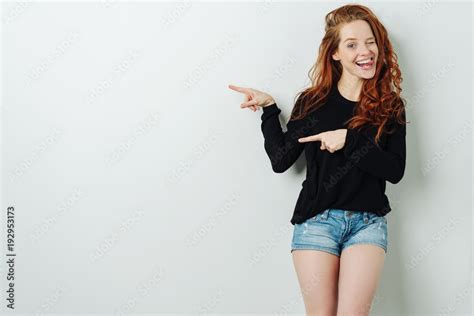 Laughing young woman pointing to copy space Stock-Foto | Adobe Stock