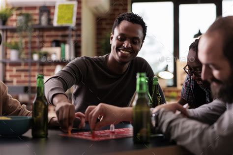 Confident smiling african american player playing boardgames with friends at home. Stock Photo ...