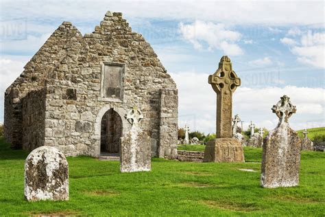 Ancient stone roofless church with celtic crosses in a grassy field ...