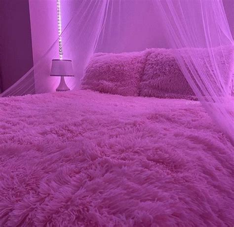 a bed with a pink comforter and mosquito netting over it's headboard