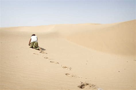 Man crawling on all fours alone in the desert stock photo