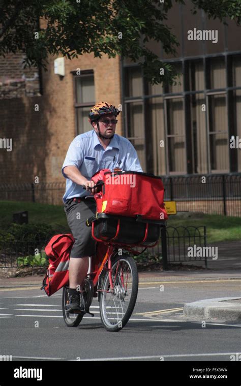 Postman on his bike Stock Photo - Alamy