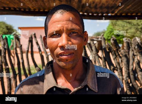 village african man standing under the metal shed in front of a wooden log fence Stock Photo - Alamy