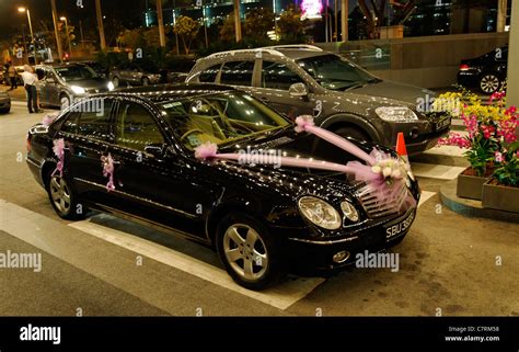 Black wedding limousine with pink ribbons, reflecting rows of hotel lights in Singapore Stock ...