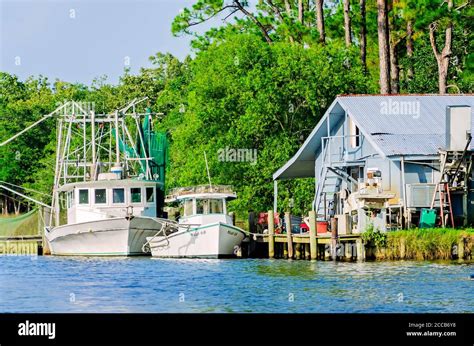 An oyster boat and shrimp boat are docked in front of a home on Fowl ...