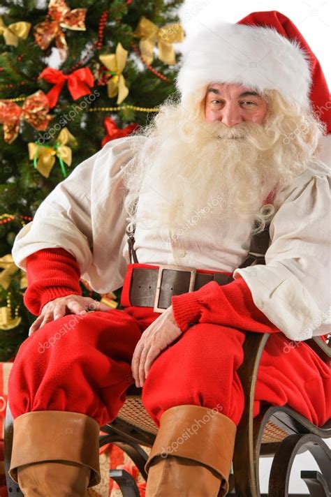 Santa Claus sitting in rocking chair near Christmas Tree — Stock Photo © HASLOO #31418345