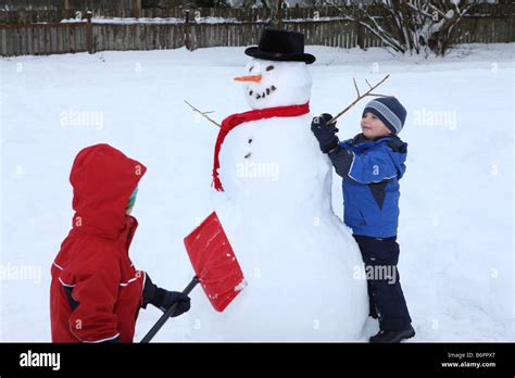 Two young boys building snowman Stock Photo - Alamy