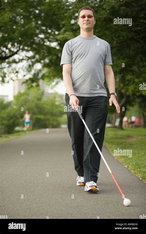 Blind man walking on a walkway with a blind person's cane Stock Photo - Alamy