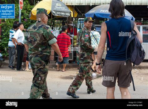 Western tourist and Cambodian military looking at each other near Siem ...