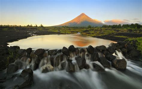 an image showing Mayon Volcano with its glowing tip as the sun slowly rises lighting the area ...