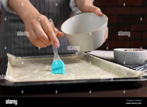 Making delicious baklava. Woman buttering dough at table, closeup Stock ...