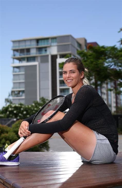 a woman sitting on the ground with a tennis racket in her hand and ...