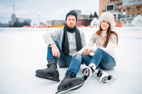 Premium Photo | Love couple in skates sitting on ice, skating rink