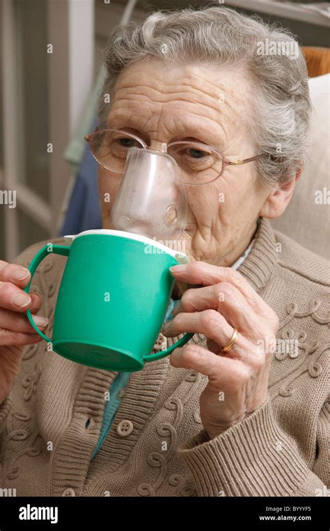 elderly woman using a steam inhaler inhaling a decongestant for colds ...