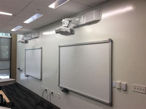 Two EPSON ultra short throw projectors both mounted to the wall in more of a conference room ...