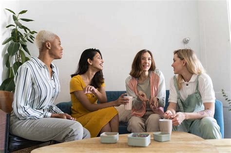 Four women sitting on couch talking stock photo