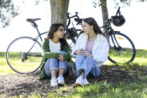 Two young women sitting outside in a park talking – Mindframe online image collection