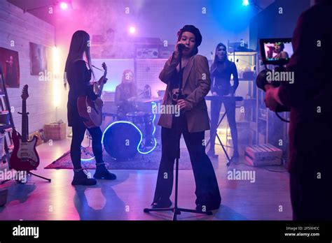 Singer singing in microphone and performing with her music band in the night club Stock Photo ...