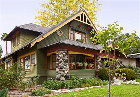 a green house with brown trim and stone accents on the front porch is ...