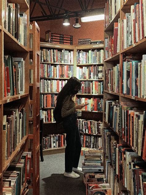 a person standing in front of a book shelf filled with books and looking at something