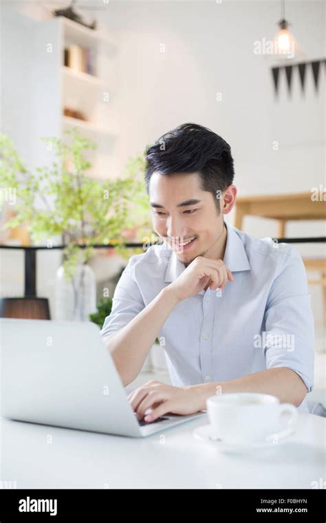 Happy young man using laptop in coffee shop Stock Photo - Alamy