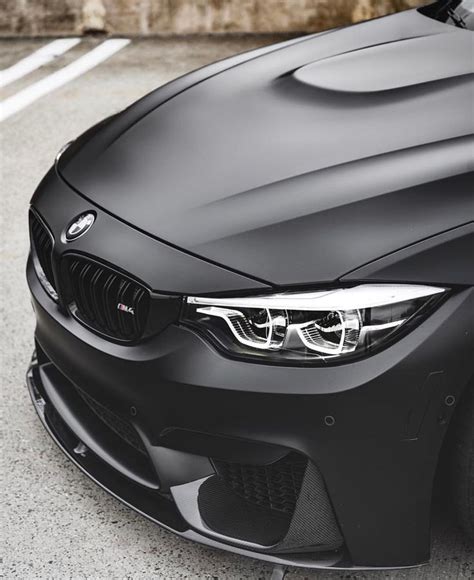 the front end of a black bmw car parked in a parking lot next to a building