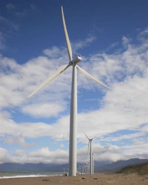 a wind turbine on the beach with clouds in the background