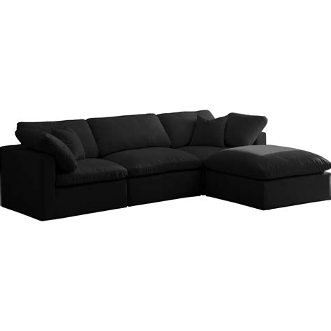 a black sectional couch with pillows on the top and bottom part, facing away from the camera