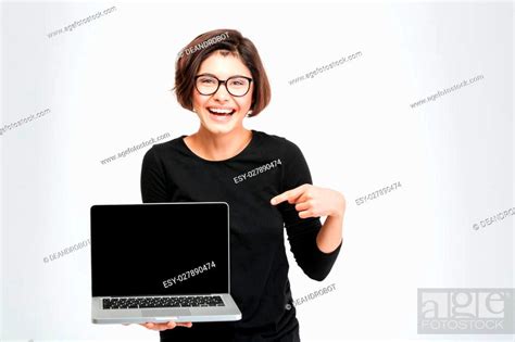 Laughing woman pointing finger on blank laptop computer screen isolated on a white background ...