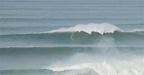 Surfer is riding a giant big wave in Nazare, Portugal. Biggest waves in the world. Touristic ...